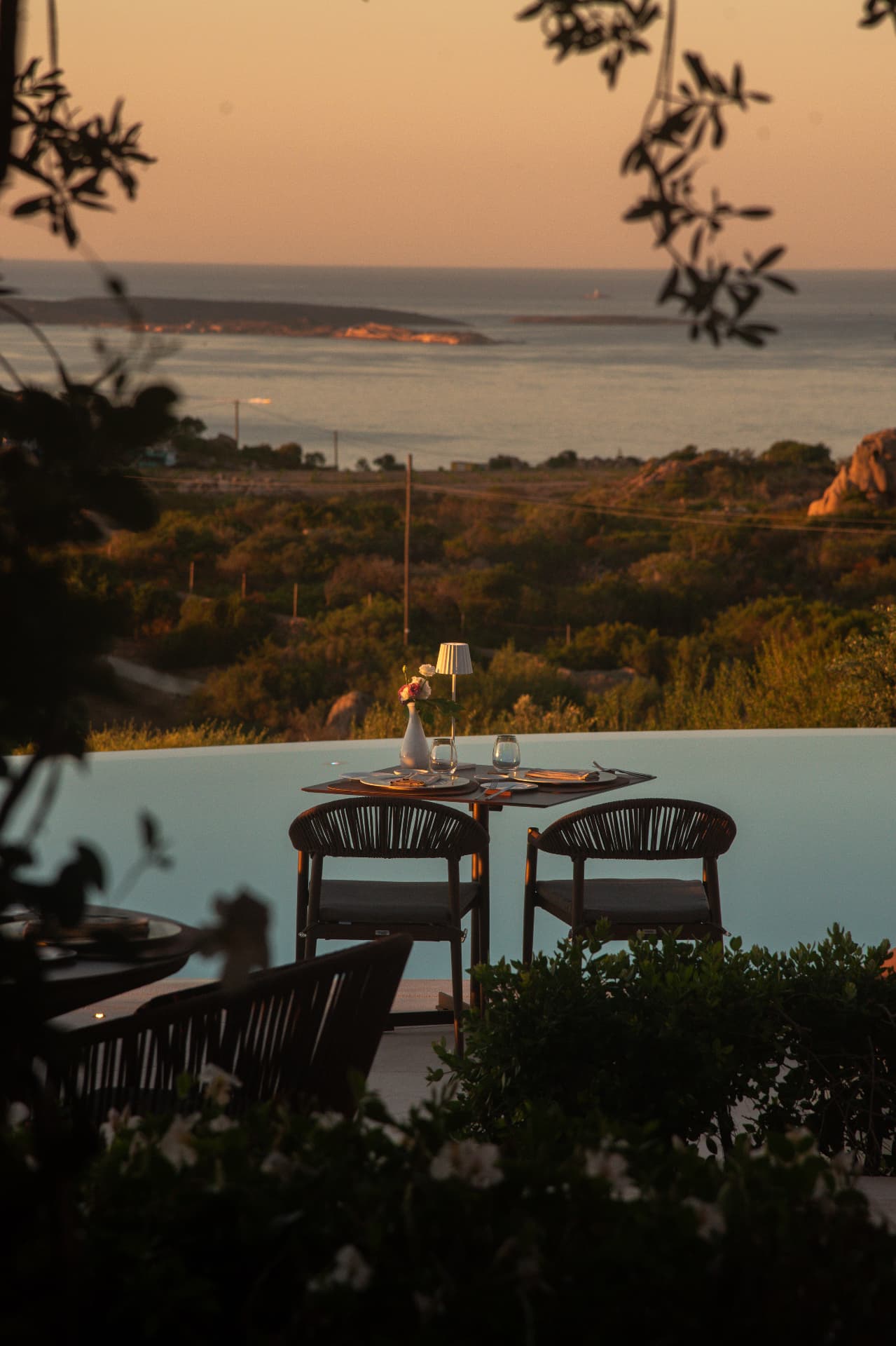 Tavolo apparecchiato sulla terrazza di Gourmet Corallia con vista sul mare al tramonto